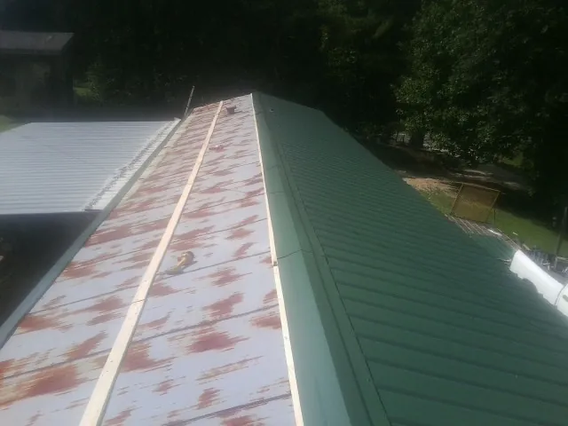 Old rusted panels beside newly installed green metal roofing — Wind Damage Roof Repair by Roofing Brothers in Browder