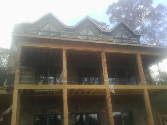 Dormers and porch framing on a large log home under construction — Roof Coating work by our crew in Browder