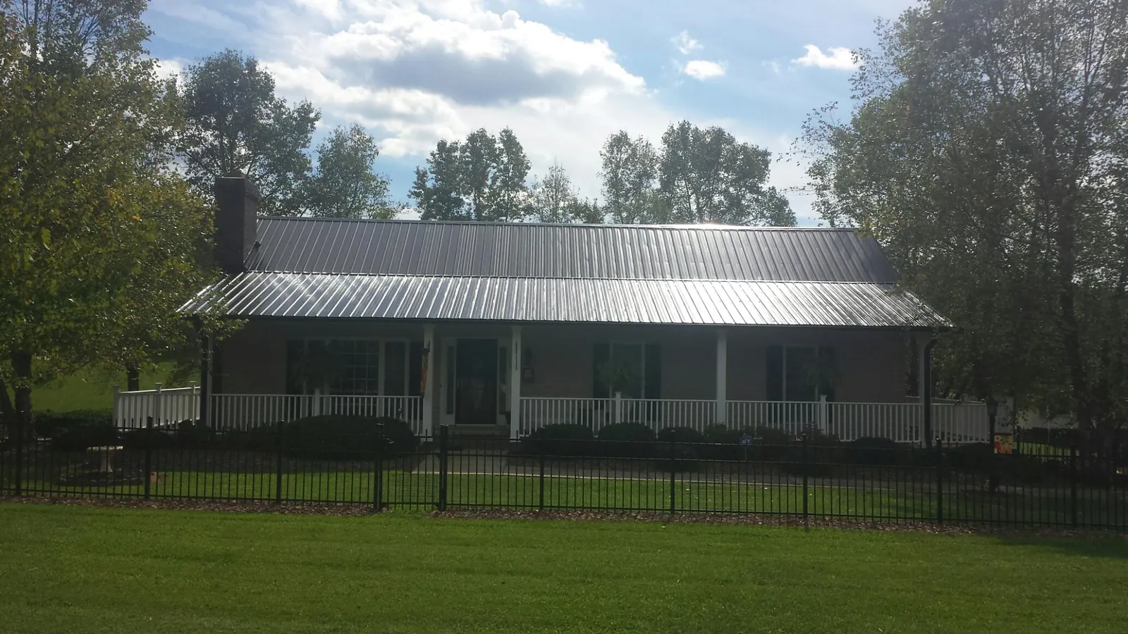 Gray metal roof on a brick ranch with a full width front porch — Gutter Guard Installation work by our crew in Browder